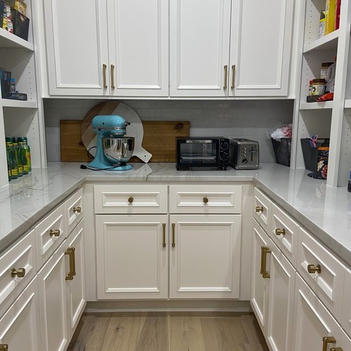 White tile backsplash and engineered hardwood in a organized pantry